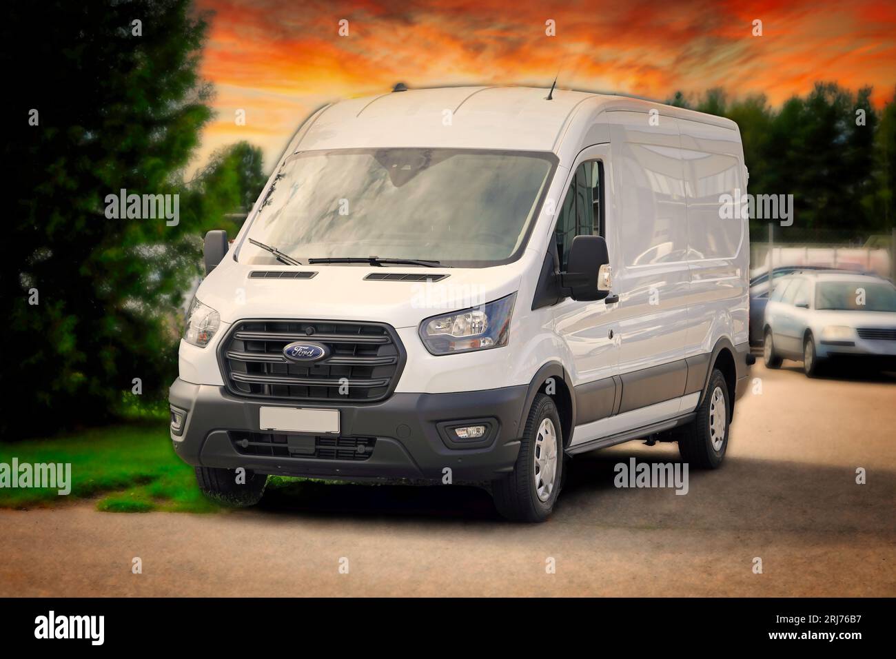 Weißer Ford Transit 350 Van des Jahres 2023, der draußen bei einem Autohändler geparkt ist. Untergehender Himmel, Bewegungsunschärfe, verschwommener Hintergrund hinzugefügt. Salo, Finnland. August 13-2023 Stockfoto