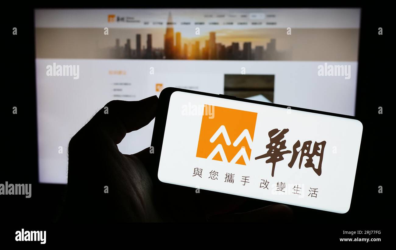 Person, die ein Mobiltelefon mit dem Logo von China Resources Holdings Company Limited (CRC) auf dem Bildschirm vor der Webseite hält. Konzentrieren Sie sich auf das Display des Telefons. Stockfoto
