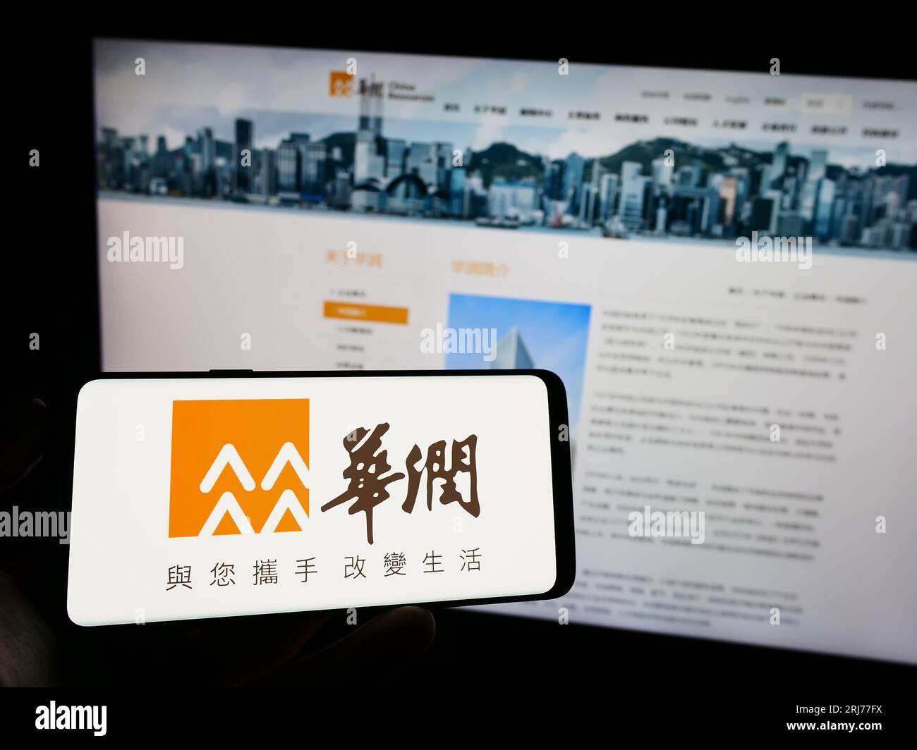 Person, die ein Mobiltelefon mit dem Logo von China Resources Holdings Company Limited (CRC) auf dem Bildschirm vor der Webseite hält. Konzentrieren Sie sich auf das Display des Telefons. Stockfoto