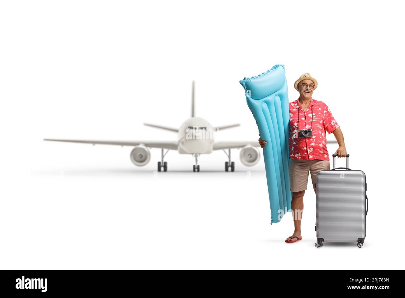 Glücklicher reifer männlicher Tourist, der eine aufblasbare Matratze und einen Koffer vor einem Flugzeug auf weißem Hintergrund hält Stockfoto