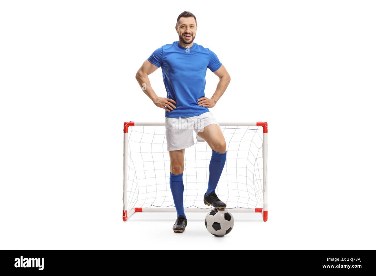 Porträt eines Fußballspielers in voller Länge, der mit einem Ball vor einem Minitor auf weißem Hintergrund posiert Stockfoto