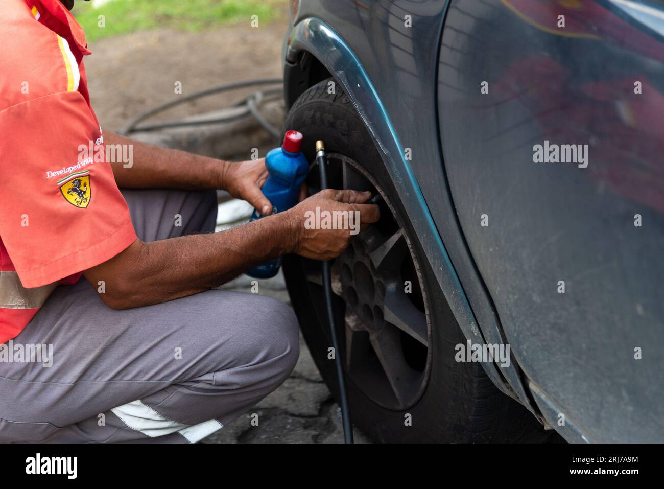 Salvador, Bahia, Brasilien - 11. August 2023: Ein Arbeiter an einer Tankstelle wird gesehen, wie er auf der Avenida Tancredo Neves in der Stadt Salvador, B, einen Autoreifen aufpumpt Stockfoto