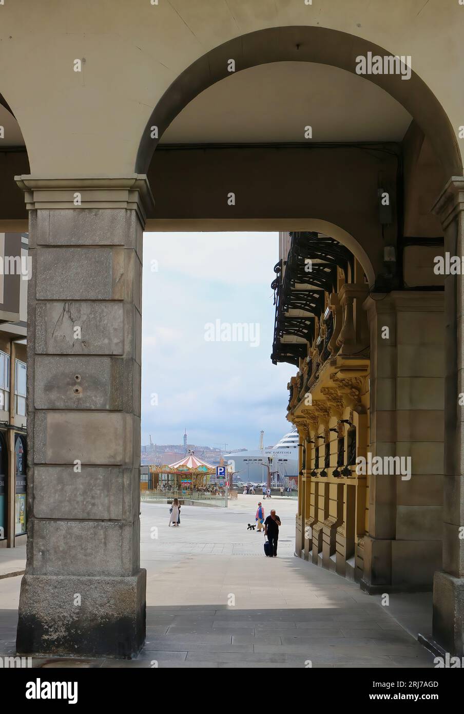 Blick durch Bögen von der Plaza de Maria Pita in Richtung Hafen mit dem Kreuzfahrtschiff MSC Virtuosa, das An Einem Coruña Galicia Spanien ankerte Stockfoto