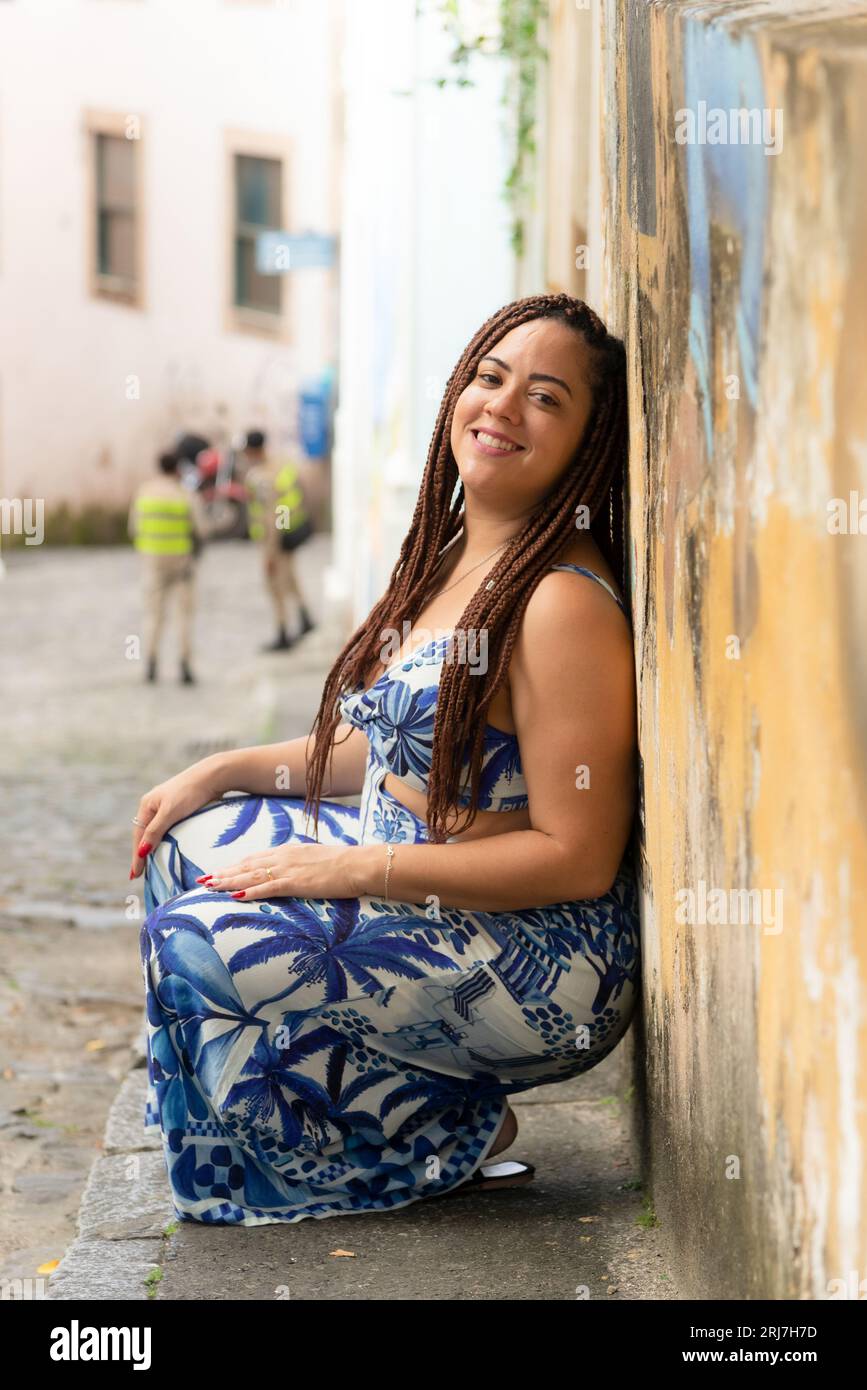 Porträt einer hübschen Frau, die sich in einem alten Haus an eine Wand beugt. Reisende Person. Pelourinho, Brasilien. Stockfoto