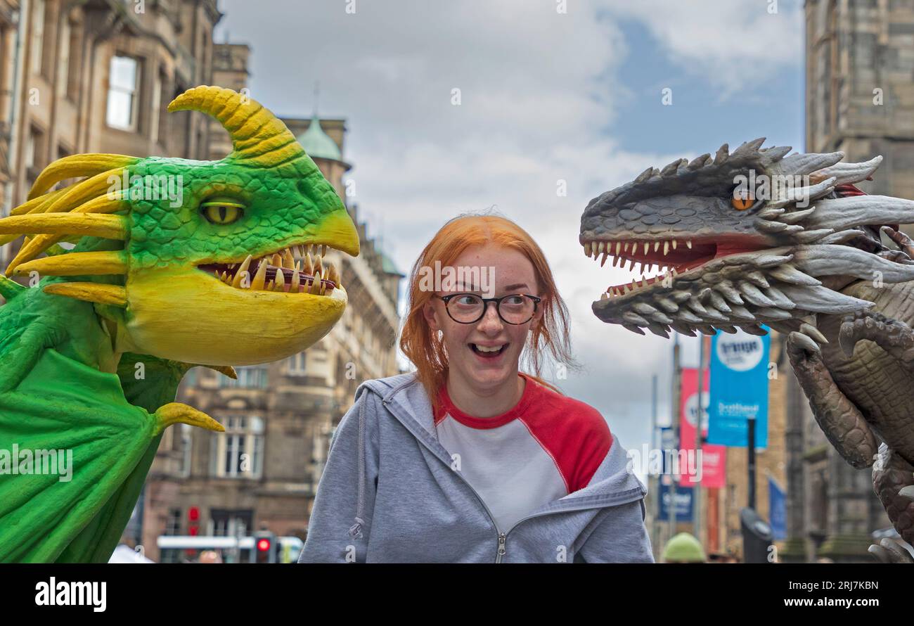 Edinburgh Fringe, Royal Mile, Schottland. August 2023. Elizabeth Taylor aus Bournemouth trifft auf Dragons Luna und Roger auf der Royal Mile. Luna (grün und gelb) tritt mit Teach Rex Live-A Dragon's Tale auf, im Greenside @ Nicolson Square- Emerald Theatre am 221-26. August. https://teachrex.co.uk/dragons/ dieser interaktive, nagelscharfe Schwanz über Tapferkeit, Neugier und familiäre Liebe wird von Lehrern geschaffen, um junge Köpfe für kreatives Schreiben zu inspirieren. Teach Rex ist das mehrfach preisgekrönte Team hinter verschiedenen pädagogischen Dinosaurier-Shows, die die UK Credit: Archwhite/Alamy Live News besucht haben Stockfoto