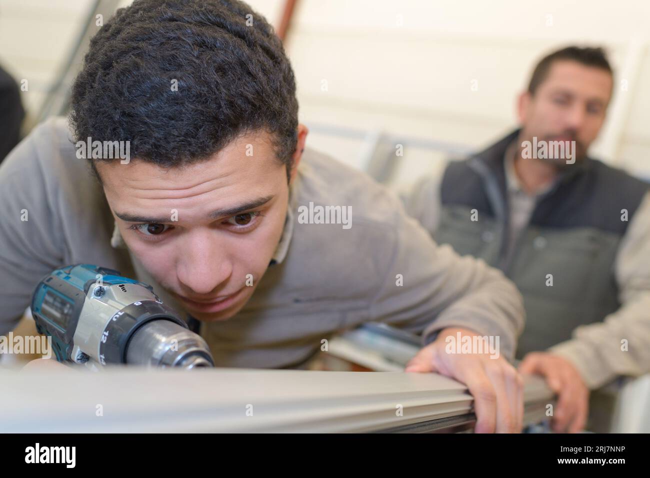 Gestresste junge Arbeitskraft mit Bohrer Stockfoto