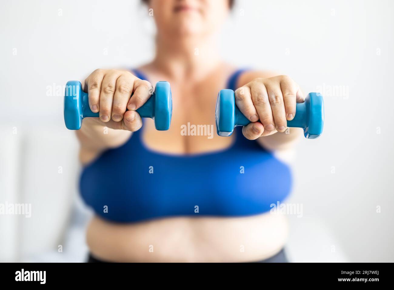 Nahaufnahme einer fetten Frau, die Kurzhanteln hält. Gewichtsverlust-Übergewicht-Problemkonzept der Frau. Stockfoto