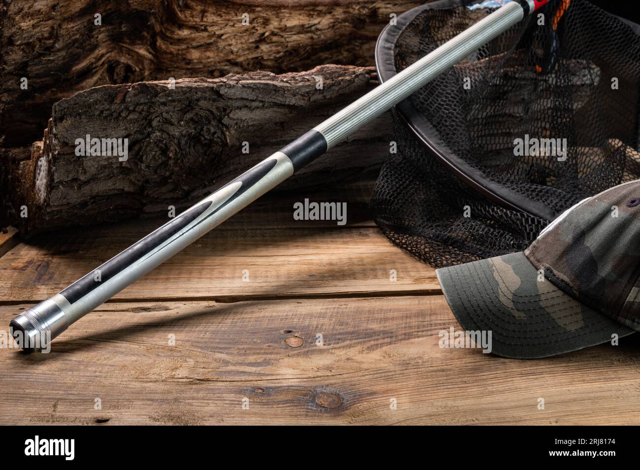 Der Hintern einer Angelrute auf einem Holzstumpf. Tarnkappe für Fischer. Bildschirmschoner für Angelausflüge. Vorderansicht. Stockfoto