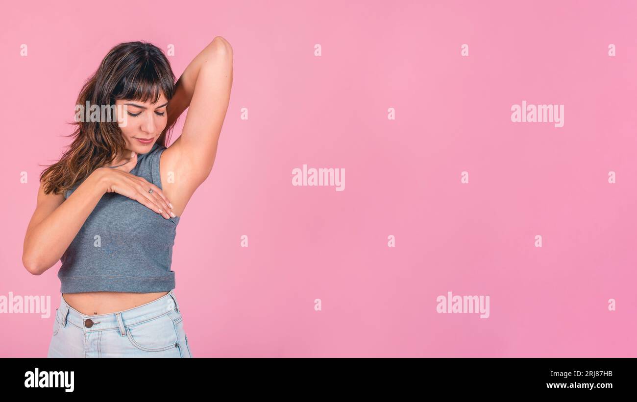 Frau, die eine Brust-Selbstuntersuchung vor pinkfarbenem Hintergrund macht. Speicherplatz kopieren Stockfoto