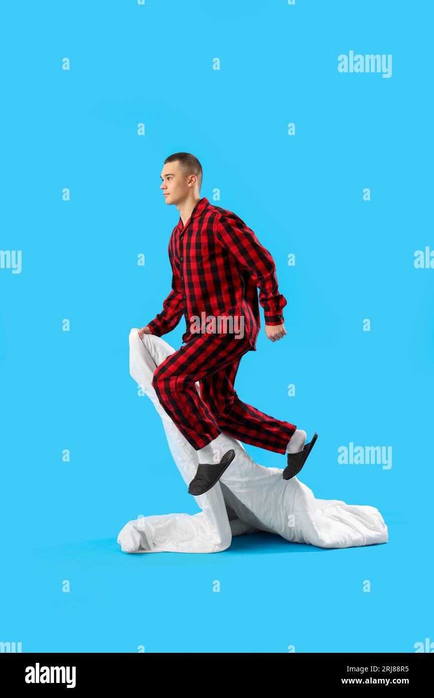Springender junger Mann mit Decke auf blauem Hintergrund Stockfoto