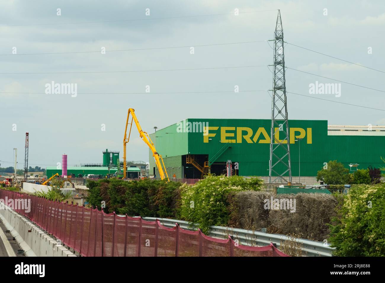 Brescia, Italien - 13. Juni 2023: Produktionsgebäude des Feralpi-Unternehmens, das Stahlerzeugnisse herstellt. Blick auf ein grünes Gebäude mit einem gelben Schild Stockfoto