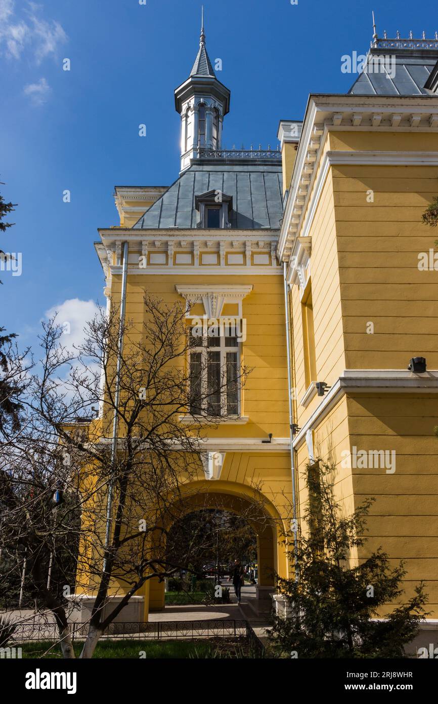 Ein gelbes, einstöckiges Gebäude, das von der warmen Sonne eines klaren blauen Himmels beleuchtet wird Stockfoto