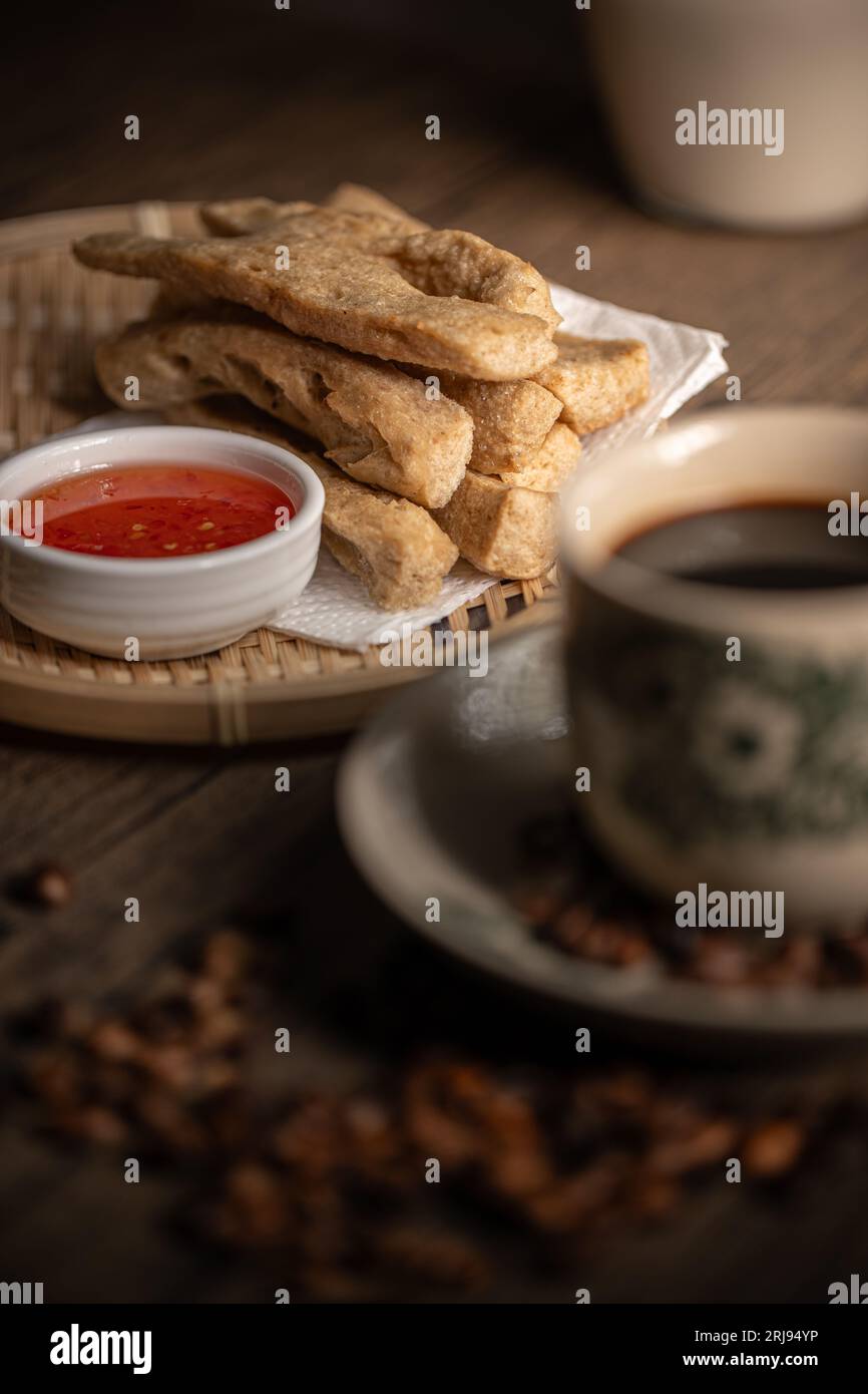 Keropok Lekor oder gebratener Fischkuchen auf einem Rattan-Teller mit einer süßen Chili-Sauce und auf einem Holztisch. Malaysische Snacks. Asiatische Lebensmittel. Stockfoto