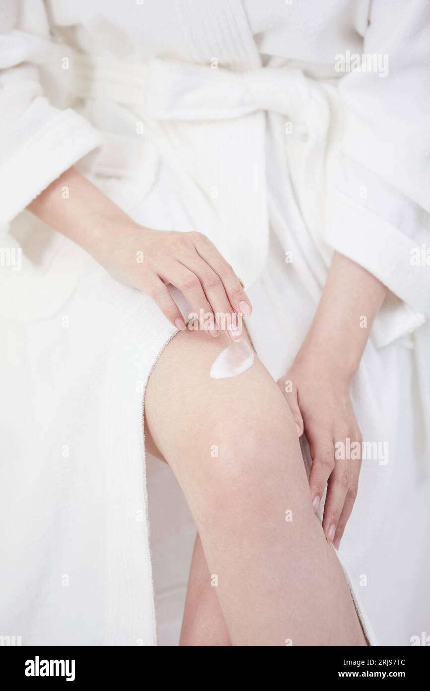 Beauty Concept Foto von koreanerin asain schöne Frau, die ihre Beine mit Feuchtigkeit versorgt Stockfoto