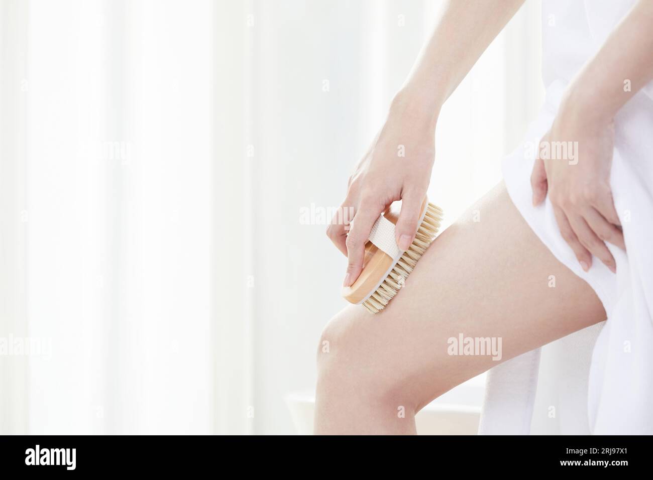 Beauty Concept Foto von koreanerin, die eine schöne Frau mit einem Pinsel ihre Beine schrubbt Stockfoto