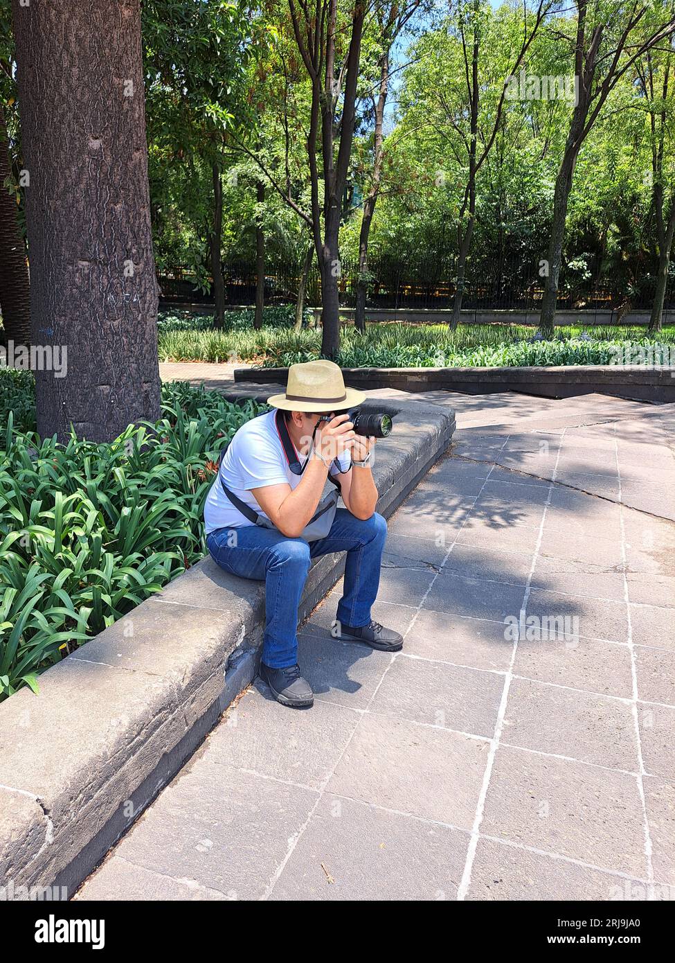 Dunkelhaariger Latino-Erwachsener ist Outdoor-Fotograf mit professioneller Kamera. Lächeln! Stockfoto