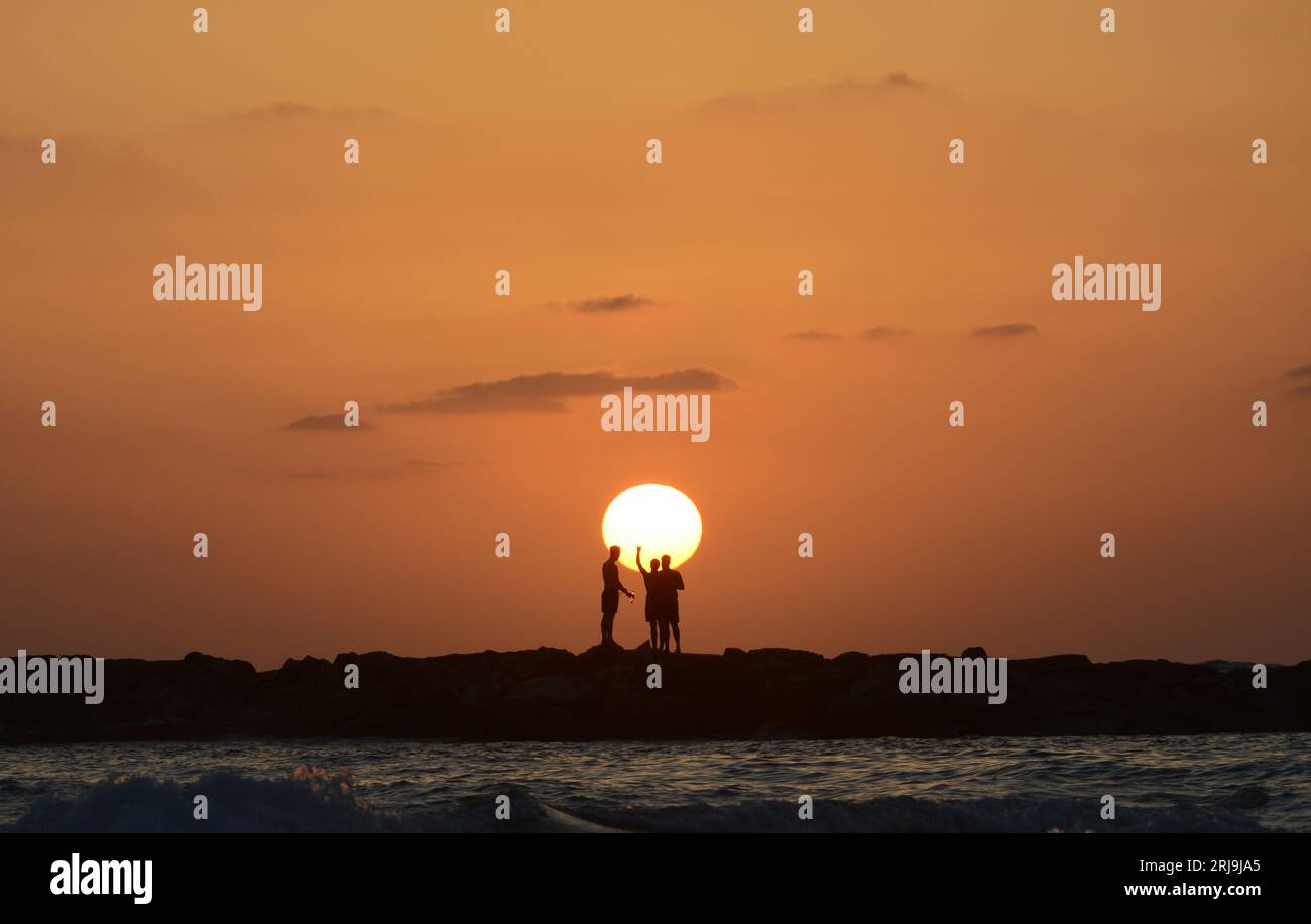 Freunde genießen den wunderschönen Sonnenuntergang am Strand in Tel-Aviv, Israel. Stockfoto