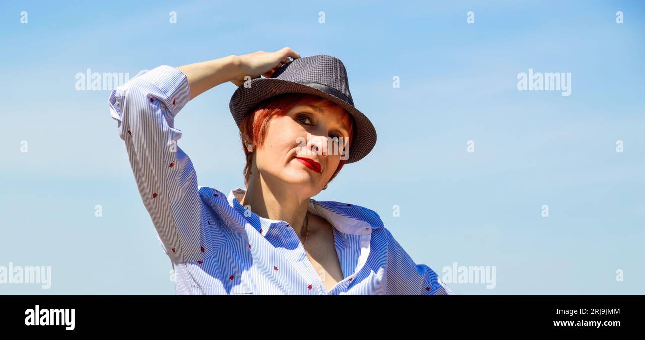 Porträt der russischen rothaarigen Frau mit hellen Make-up in hut und blaue Bluse auf einem Hintergrund von grünen Feld Stockfoto