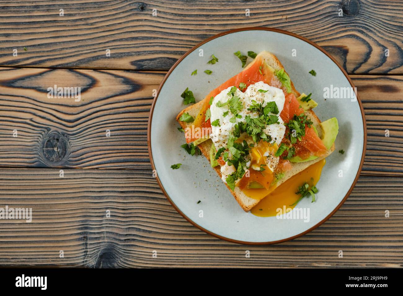 Blick von oben auf das Sandwich mit Forellenscheiben, Avocado und pochiertem Ei Stockfoto