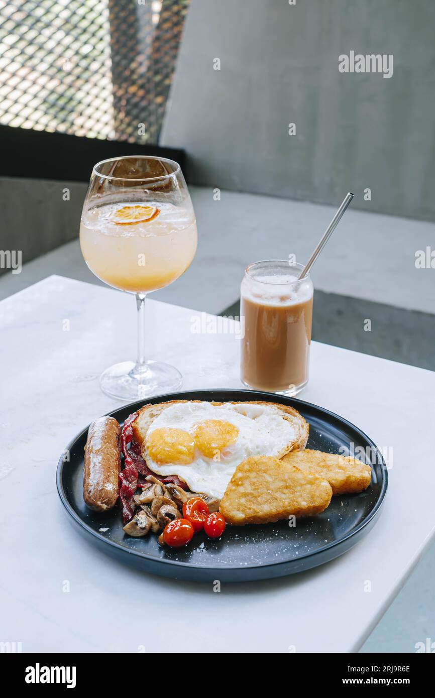 Porträt- oder Vertikalaufnahme von 1 Set Speisen und Getränke enthält ein komplettes englisches Fry-Up-Frühstücksmenü, EismischCappucino und tropische Sangria Stockfoto