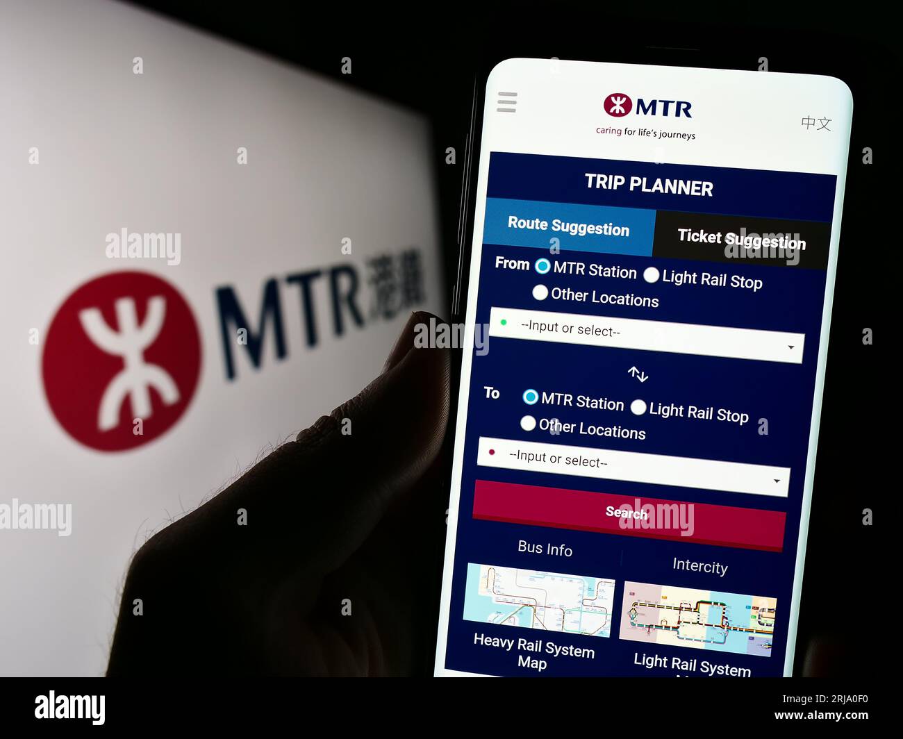 Person, die ein Mobiltelefon mit Webseite der chinesischen Eisenbahngesellschaft MTR Corporation Limited auf dem Bildschirm mit Logo hält. Konzentrieren Sie sich auf die Mitte der Telefonanzeige. Stockfoto