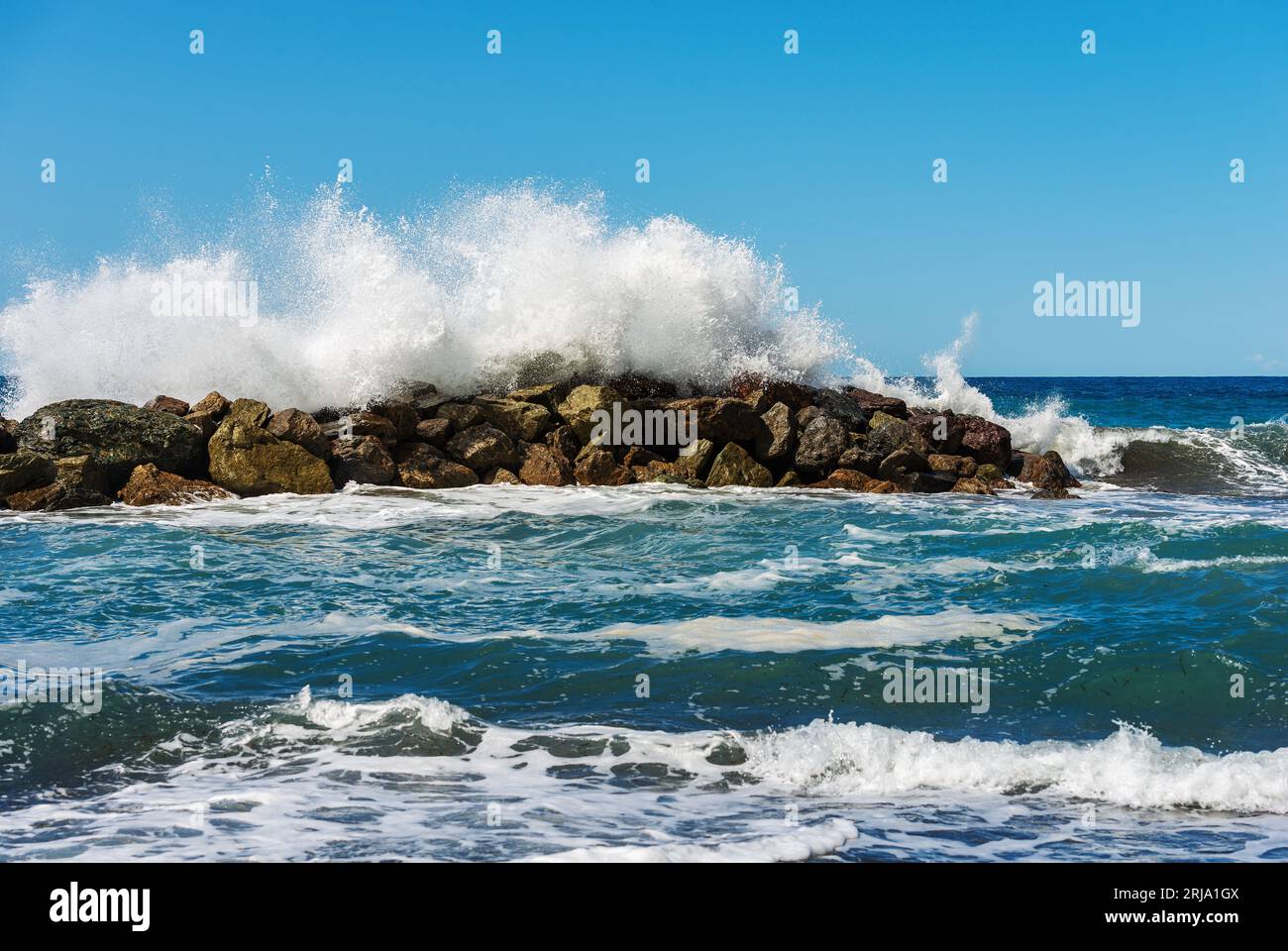 Große weiße Wellen des Meeres brechen auf den Felsen. Wellenbrecher in der Nähe des kleinen Dorfes Framura. La Spezia, Ligurien, Italien, Europa. Mittelmeer. Stockfoto