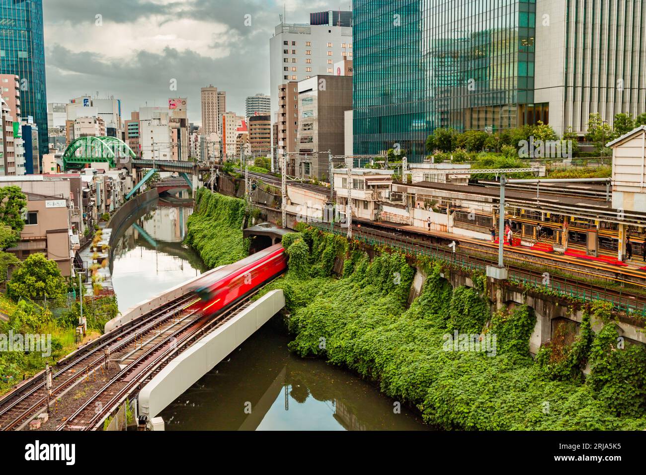 TOKIO, JAPAN - 09. AUGUST 2023: Langzeitbelichtung (verschwommene Bewegung) von U-Bahn- und Bahnzügen, die über den Kanda-Fluss an der Hijiribashi-Brücke fahren, Stockfoto