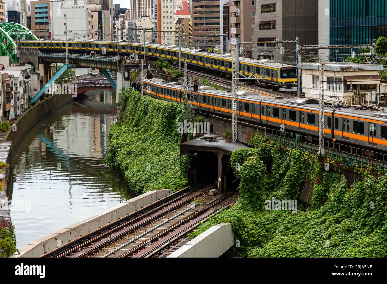 TOKIO, JAPAN - 9. AUGUST 2023: Züge, die an einer vielbefahrenen Kreuzung und einem Tunnel über den Kanda River an der Hijiribashi-Brücke in Tokio, Japan, vorbeifahren Stockfoto