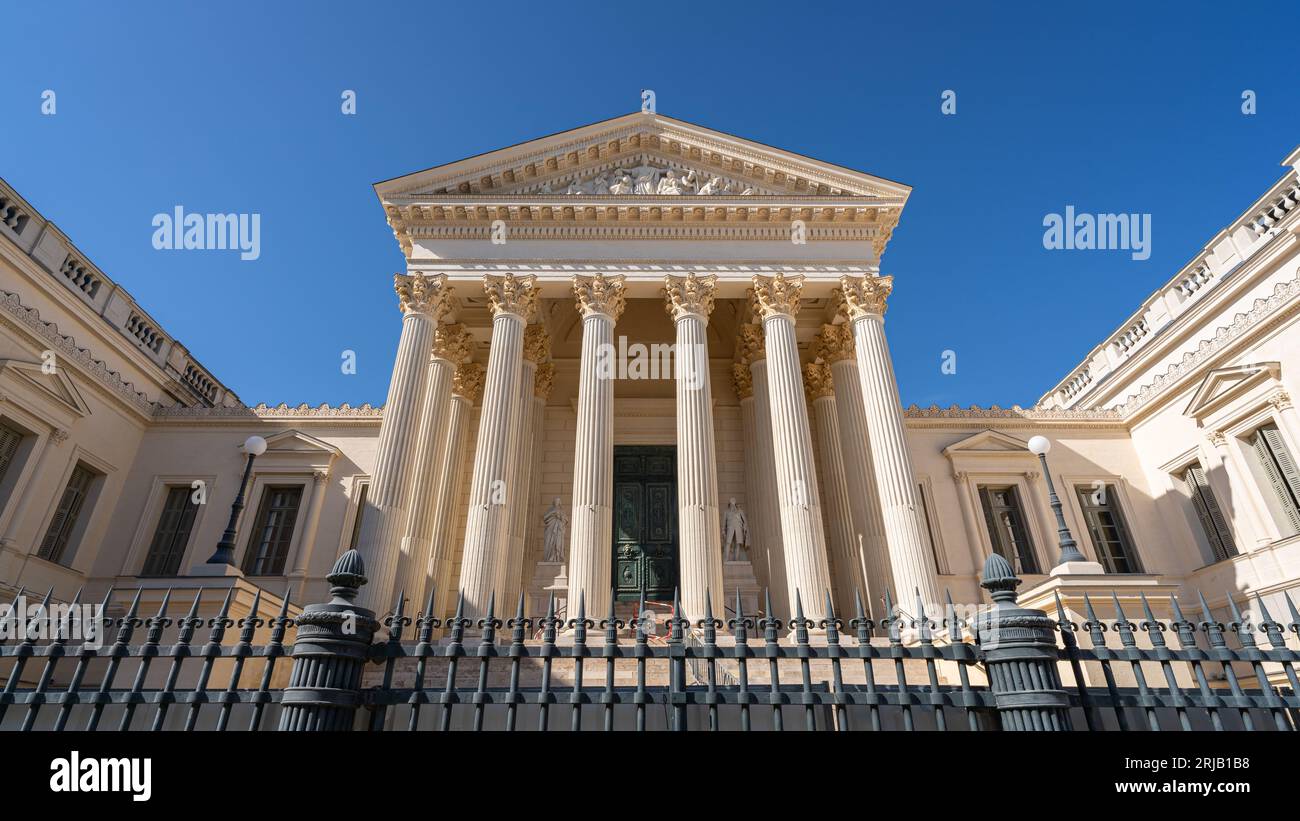 Landschaftsblick auf die klassische Steinfassade mit Säulen und Giebel, die die Gerechtigkeit des alten Gerichtsgebäudes darstellen, ein Wahrzeichen von Montpellier Stockfoto