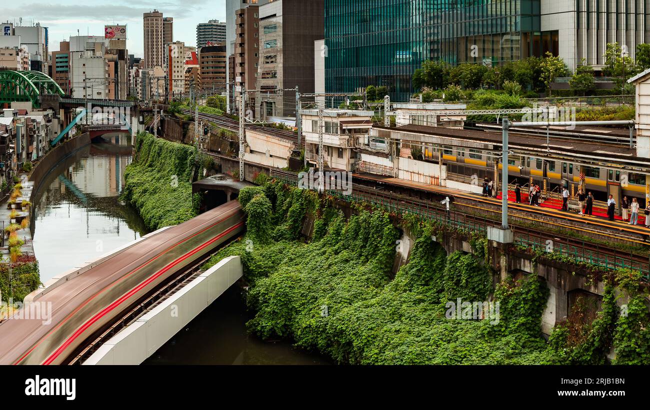 TOKIO, JAPAN - 09. AUGUST 2023: Langzeitbelichtung (verschwommene Bewegung) von U-Bahn- und Bahnzügen, die über den Kanda-Fluss an der Hijiribashi-Brücke fahren, Stockfoto