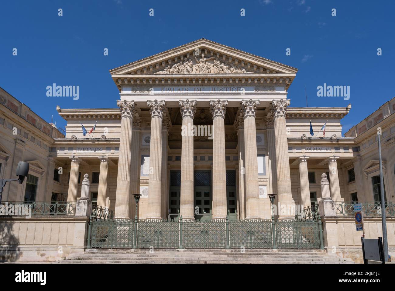 Nîmes, Gard, Frankreich - 08 17 2023 : Landschaftsansicht der klassischen Steinfassade mit Säulen und Giebel, die die Justiz des historischen Gerichtsgebäudes repräsentieren Stockfoto