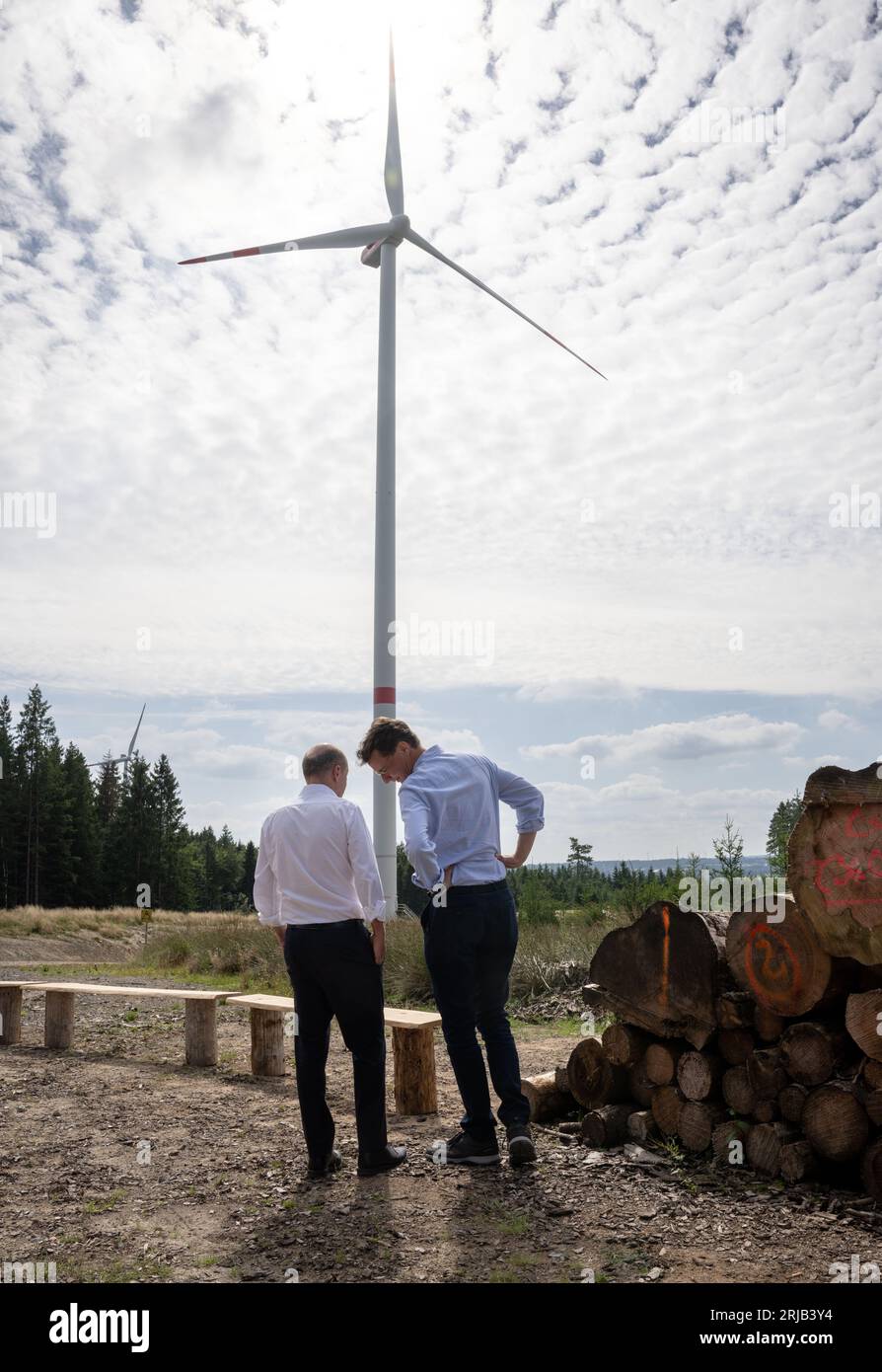 Simmerath, Deutschland. August 2023. Bundeskanzler Olaf Scholz (SPD, l) und der Ministerpräsident von Nordrhein-Westfalen, Hendrik Wüst (CDU), sprechen während ihres Besuchs in einem kommunalen Windpark. Die kleine Stadt mit mehr als 15.000 Einwohnern macht Gewinne, indem sie das Waldland in gemeinschaftlichem Besitz an den Betreiber vermietet. Ein Teil der Einnahmen fließt in den kommunalen Haushalt und ermöglicht niedrige Immobilien- und Gewerbesteuern. Quelle: Bernd Thissen/dpa/Alamy Live News Stockfoto