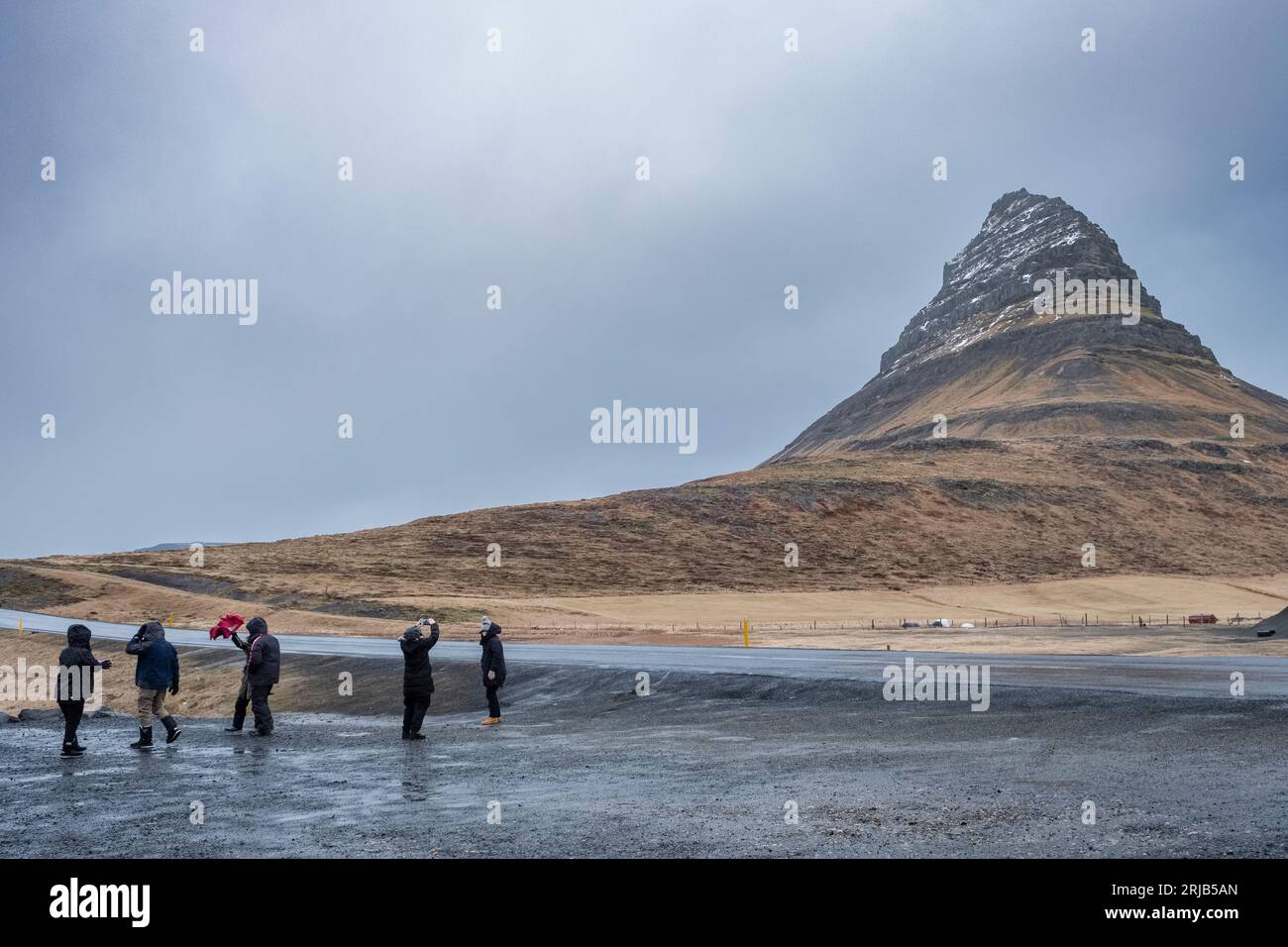 Touristen besuchen Kirkjufell (Kirchenberg) auf der Halbinsel Snæfellsnes, Island, bei nassen und windigen Bedingungen. Schlechtes Wetter ist in dieser Gegend üblich Stockfoto
