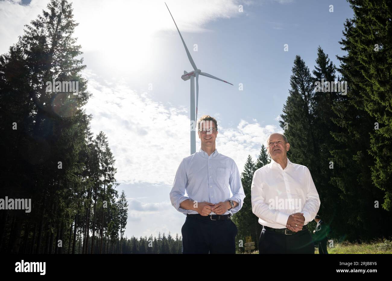 Simmerath, Deutschland. August 2023. Bundeskanzler Olaf Scholz (SPD, r) und der Ministerpräsident von Nordrhein-Westfalen, Hendrik Wüst (CDU), sprechen während ihres Besuchs in einem kommunalen Windpark. Die kleine Stadt mit mehr als 15.000 Einwohnern macht Gewinne, indem sie das Waldland in gemeinschaftlichem Besitz an den Betreiber vermietet. Ein Teil der Einnahmen fließt in den kommunalen Haushalt und ermöglicht niedrige Immobilien- und Gewerbesteuern. Quelle: Bernd Thissen/dpa/Alamy Live News Stockfoto