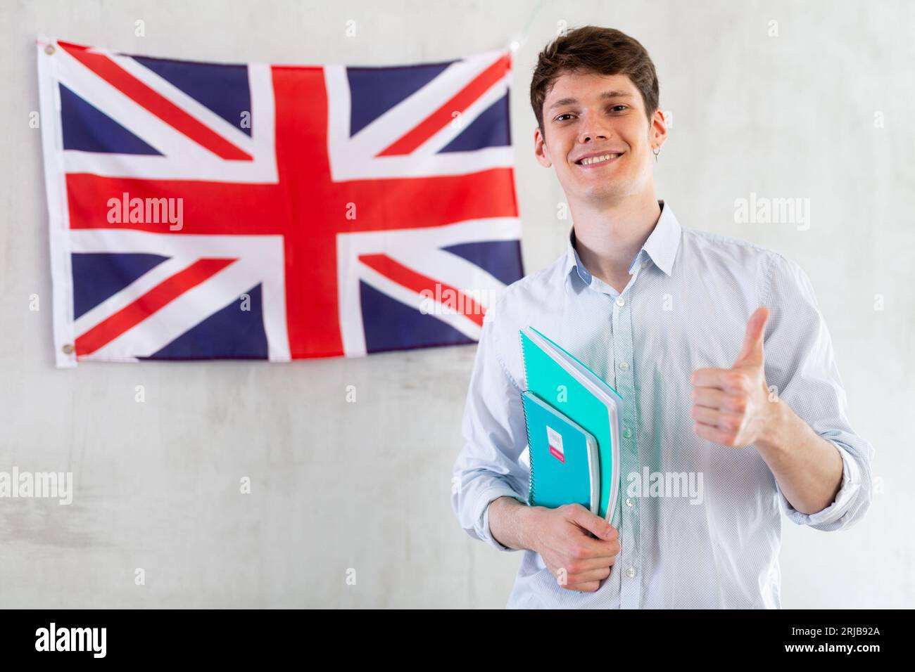 Männlicher Student mit Notizbüchern in den Händen vor dem Hintergrund der britischen Flagge Stockfoto