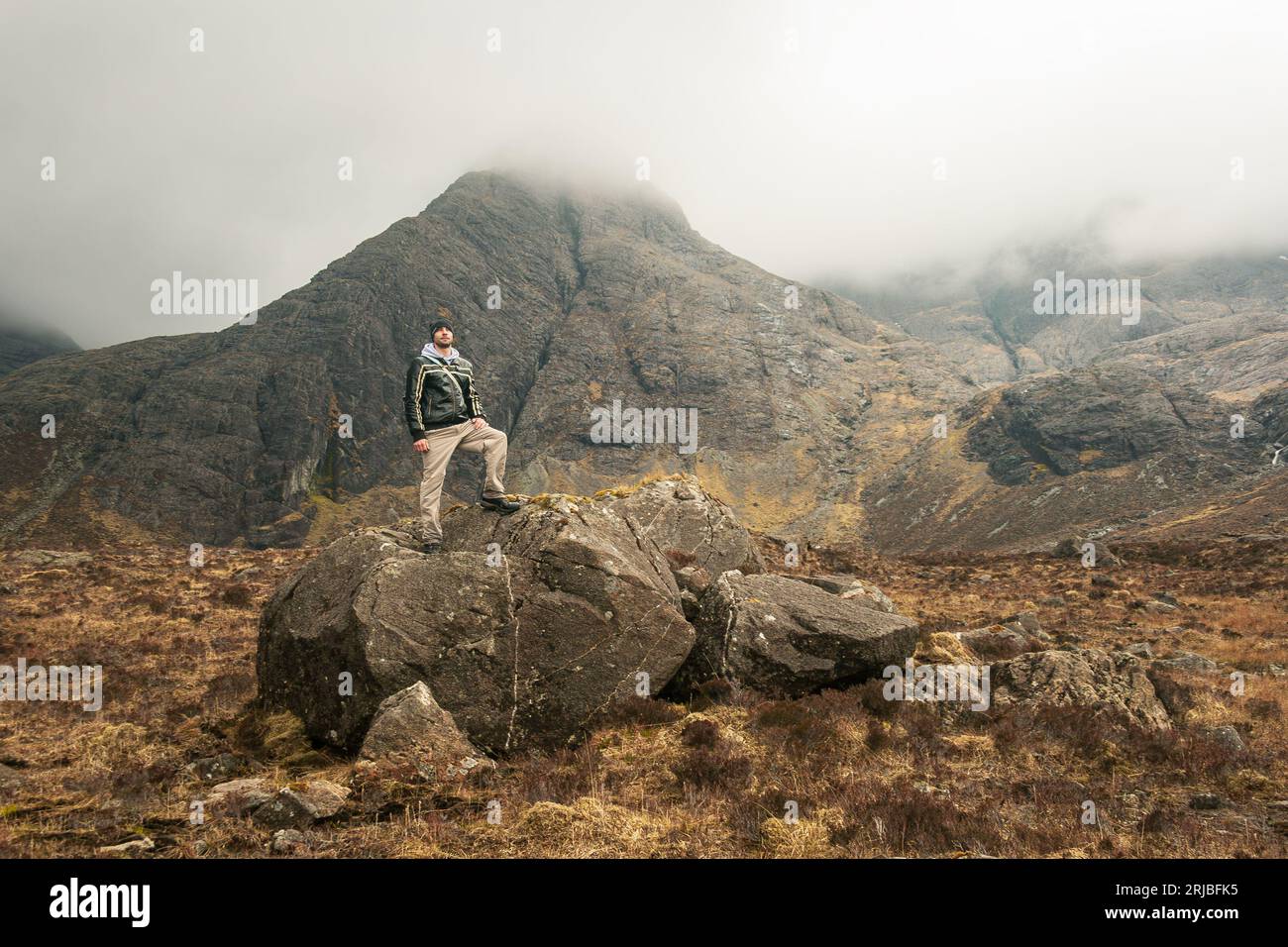 Der Mensch steht auf einem Felsen in einer nebeligen, bergigen Landschaft Stockfoto