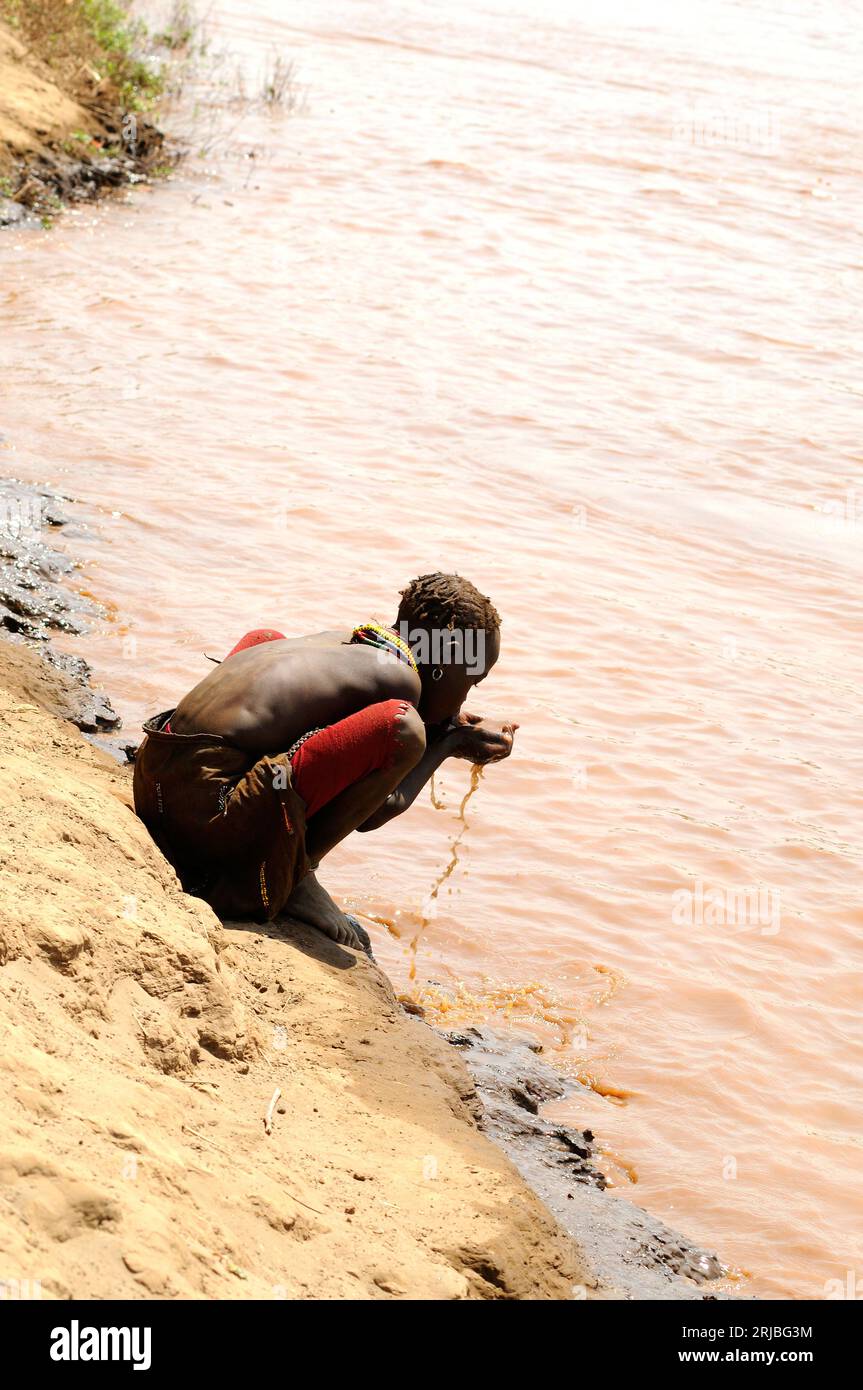 Daasanach-Junge, der verunreinigtes Wasser aus dem Omo-Fluss trinkt. Debub Omo Zone, Äthiopien. Stockfoto