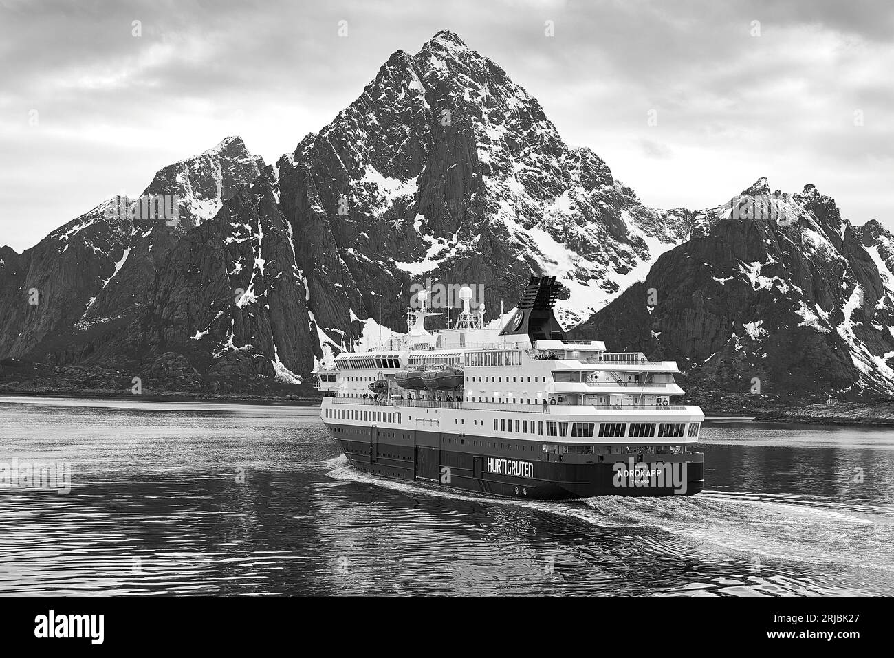 Schwarz und Foto der norwegischen Hurtigruten-Fähre, MS NORDKAPP, die von Svolvaer nach Süden dampft, dahinter schneebedeckte Berge der Lofoten-Inseln Stockfoto