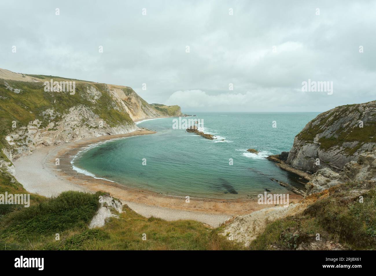 Eine halbmondförmige Meeresbucht, umgeben von einer felsigen Küste und einem Strand an der Dorset-Küste in Südengland. Befindet sich neben Durdle Door. Man O' war Beach. Hochwertige Fotos Stockfoto