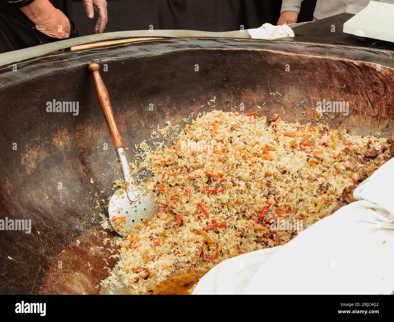 Ein großer Kessel auf einem Grillfeuer mit Usbekischen Pilaf wird in Öl gebraten Zutaten Reis Pfeffer Lamm Karotten Knoblauch Kümmel Koriander, auf einem offenen Ai gekocht Stockfoto