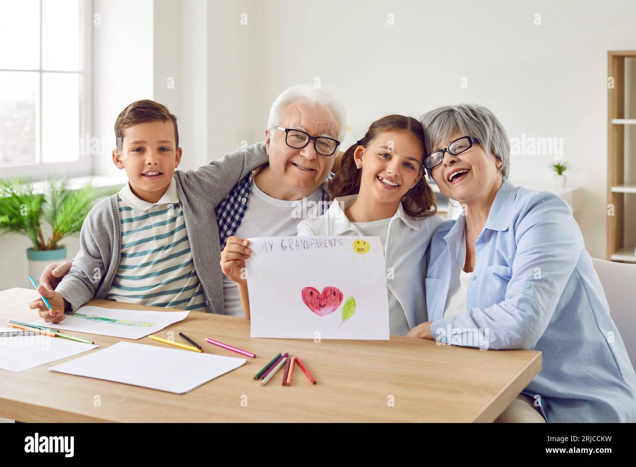 Glückliche Großeltern und Enkelkinder verbringen Zeit miteinander, zeichnen Bilder und haben Spaß Stockfoto