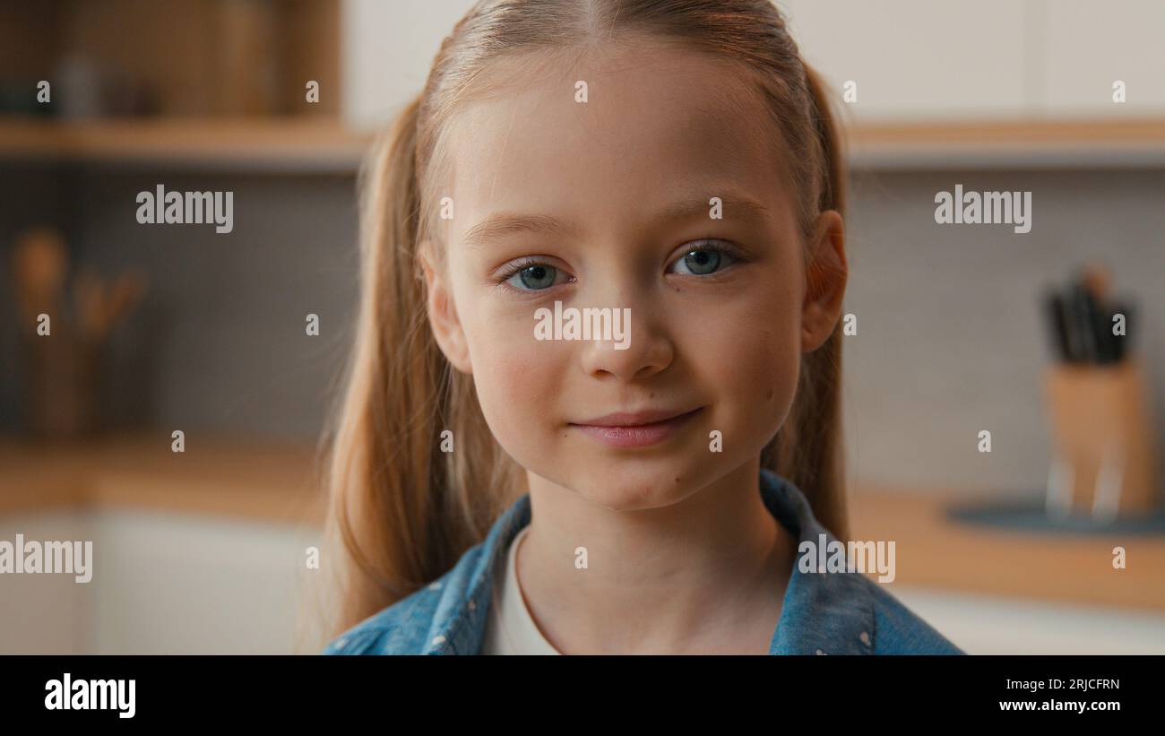 Bewegte Aufnahme Nahaufnahme kleines Schulmädchen Kaukasisches Kindermädchen lächelnd beim Blick auf Kameraportrait zu Hause Küche süße 10er Tochter adoptierte Sorgerechtskind Stockfoto