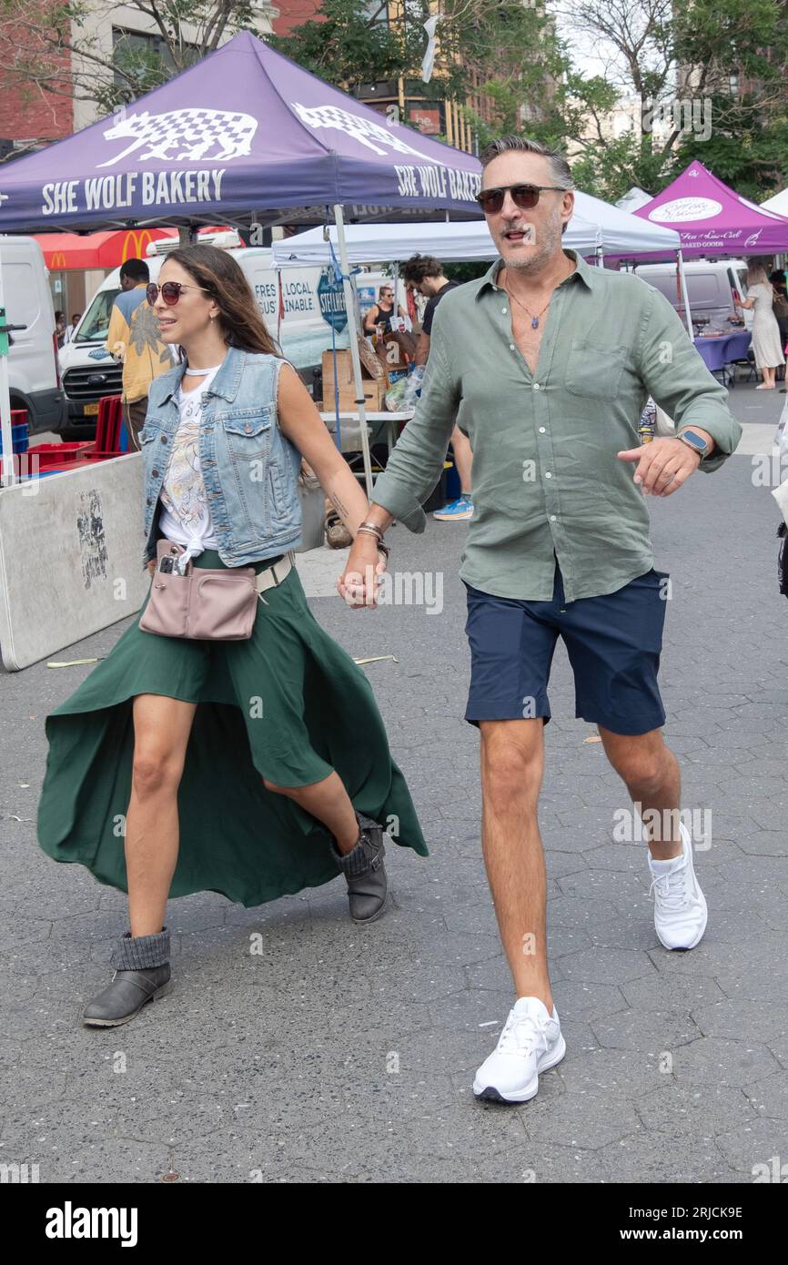 Ein attraktives Paar spaziert durch den Union Square Green Market, er trägt Shorts, sie trägt einen fließenden, enthüllenden Rock und jede mit Sonnenbrille. Stockfoto
