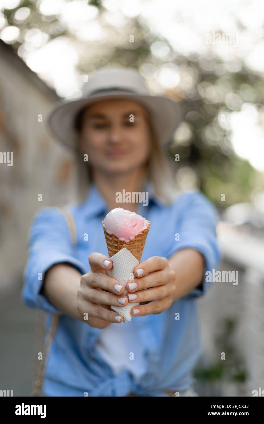 Sommerdessert und fröhliches Sommerkunstkonzept. Gesundes veganes Erdbeereis-Eis-Eis in der Hand einer jungen Frau im Hintergrund Stockfoto