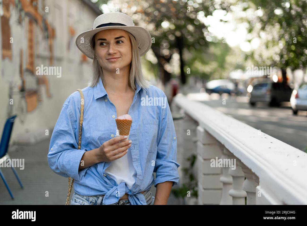 Schöne junge Frau, die Eiskegel auf der Straße hält, zuckerleckerer Appetithappen-Snack Stockfoto