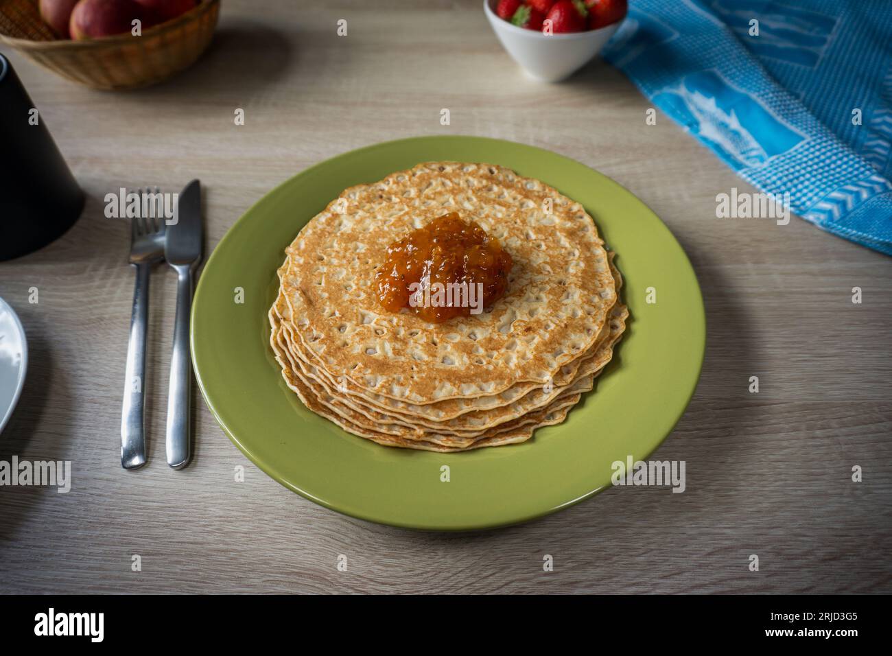 Pfannkuchen mit Cloudberry Jam auf einem grünen Teller auf einem Holztisch Stockfoto