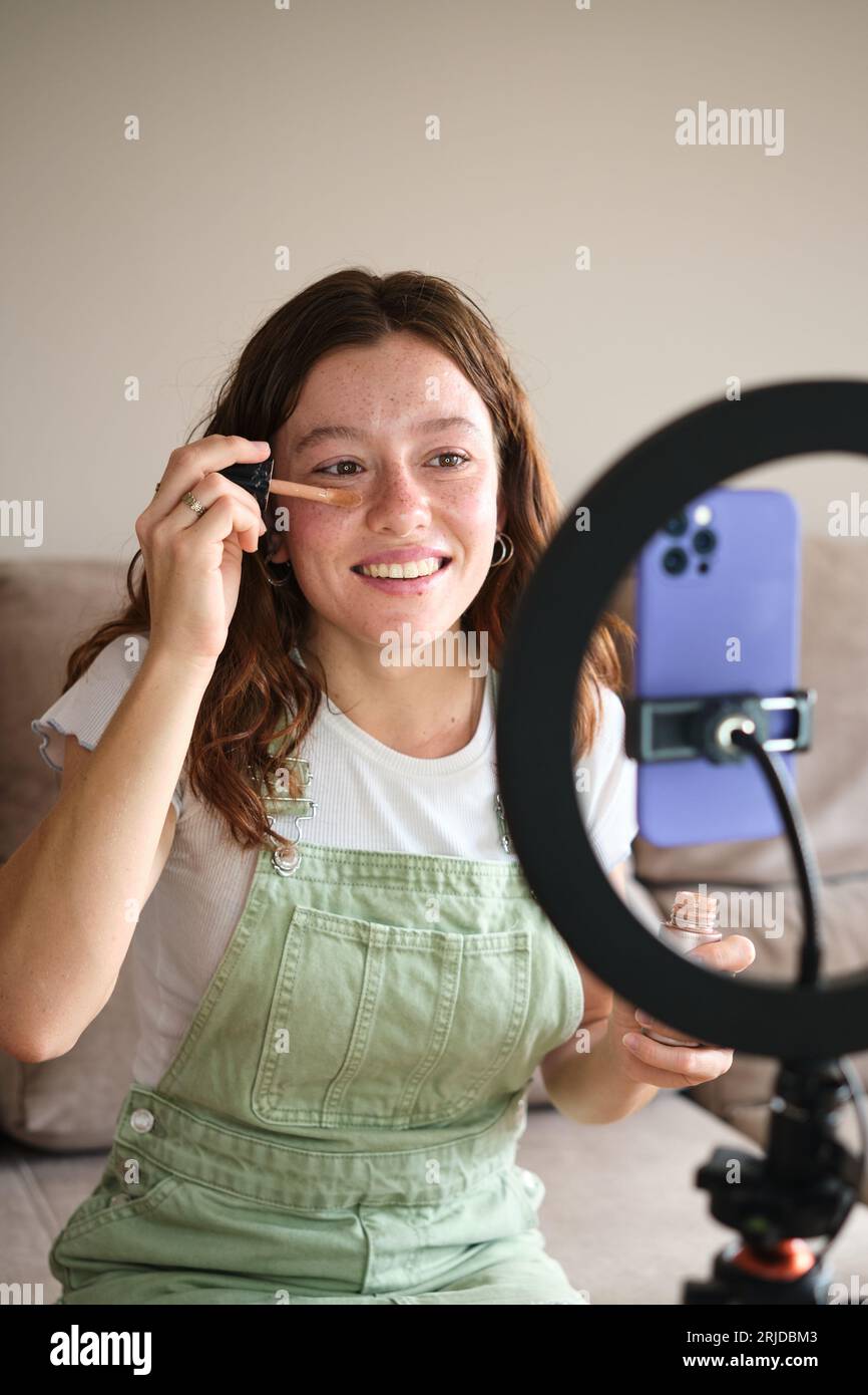 Glücklicher Influencer, der zu Hause Make-up-Tutorial auf dem Smartphone aufnimmt Stockfoto