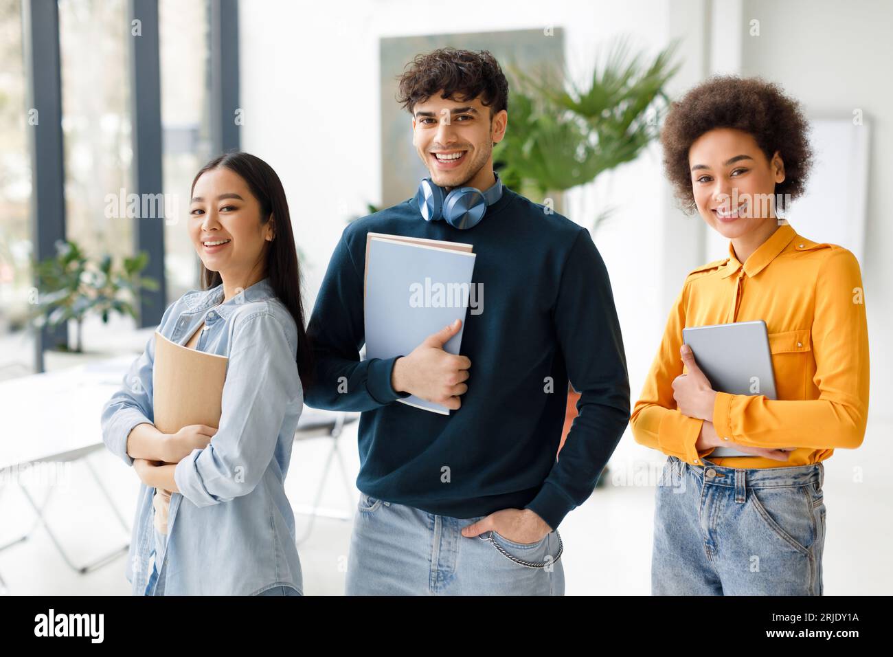 Studentschaft. Glückliche internationale Studenten posieren im modernen Publikum, verschiedene junge Menschen stehen im Klassenzimmer Stockfoto