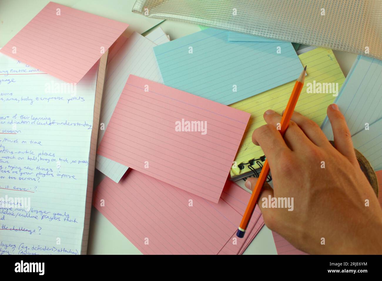 Ein Foto eines Schülers, der zu Hause an einem Schulprojekt arbeitet, mit bunten Karteikarten und Notizbuch. Stockfoto