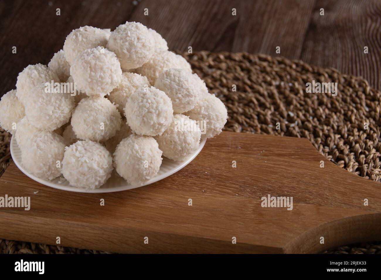 Foto süße Dessert Kokosnusskugeln auf einem Teller und einem Holzbrett liegen Stockfoto